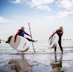 Couple holding paddleboards on the Isle of Wight